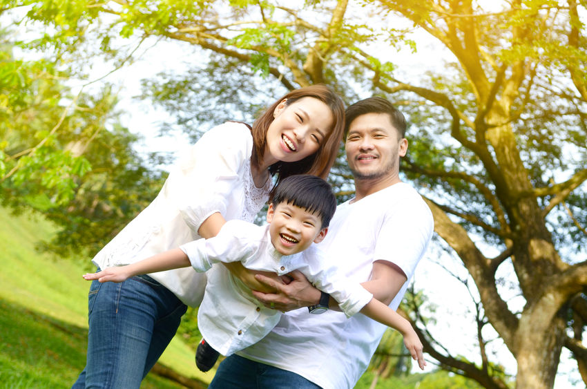 Smiling family playing together outdoors in a sunny park